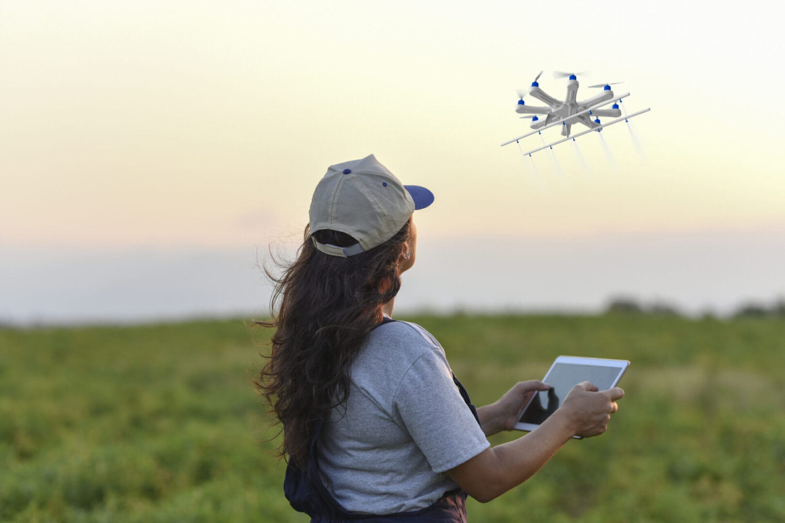 Person in field controlling drone with tablet