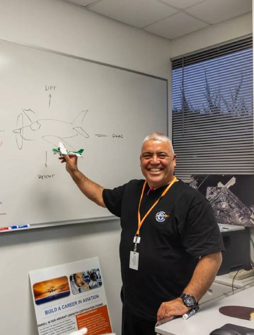 Smiling man holding model airplane by whiteboard