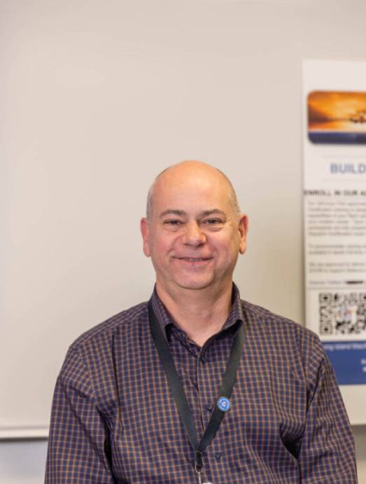 Smiling man in checked shirt wearing lanyard
